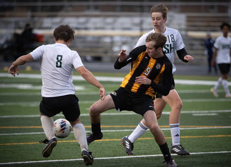 Herscher's Rowan Keigher, center, plays the ball in the box as Bishop McNamara's Matthew Buzas, left, clears it out in a regional match-up on Tuesday, October, 21, 2025