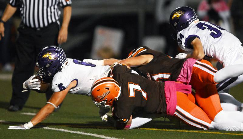 Rolling Meadows’ Peyton Wiles dives for a couple extra yards as he is tackled by Hersey players including Sebastian Debicki , front, during a football game on Friday, Oct. 18, 2024 in Arlington Heights.