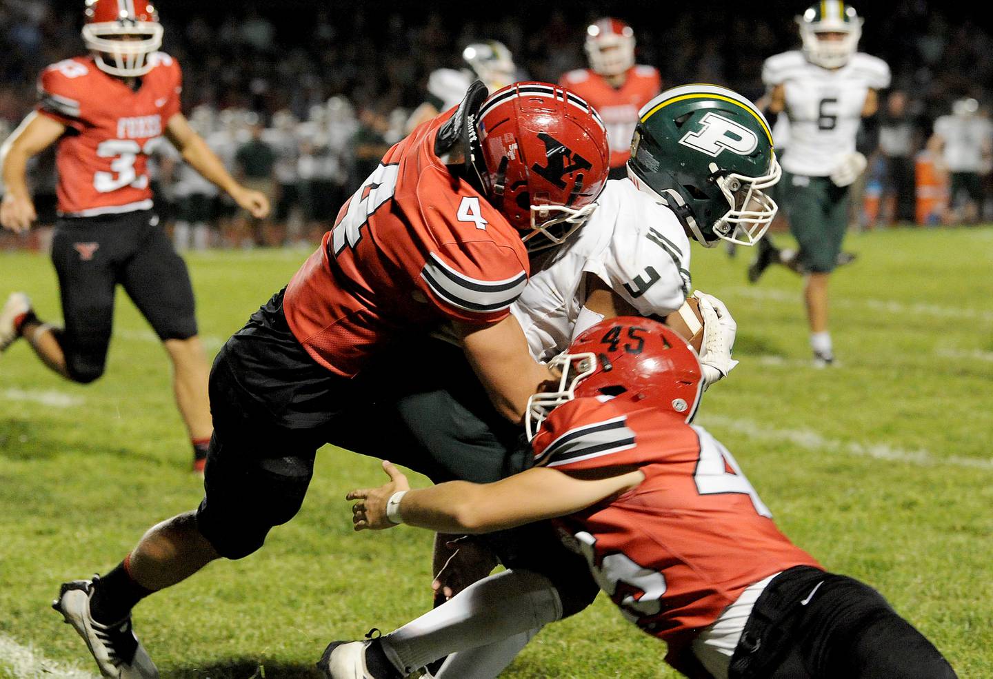 Yorkville defenders Kyle Gettemy (4) and Colten Stevens (45) bring down Plainfield Central runner Colby Williams (3) during a varsity football game at Yorkville High School on Friday, Sep. 2, 2022.