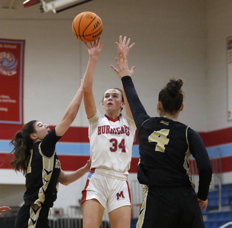 Marian Central's Juliette Huff shoots the ball between Rockford Christian's Lucy Gargani (left) and Teagan Lawver (right) during a nononference basketball game on Monday, Feb. 10, 2025, at Marian Central High School  in Woodstock.