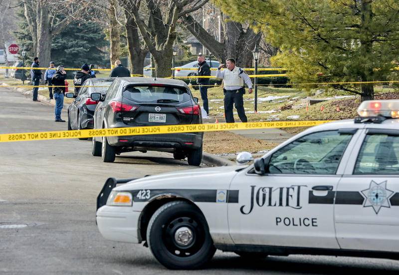 Police and investigators secure the scene of a shooting Friday, Dec. 20, 2019, as a shooting victim lays on the sidewalk along Sherwood Place in Joliet, Ill. One male was killed and a female was transported to an area hospital with an injury.