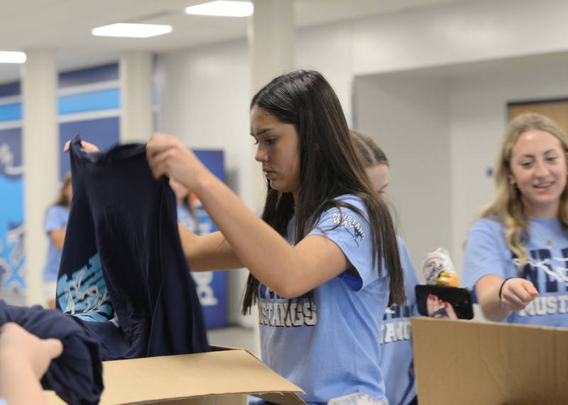 Downers Grove South High School students including Ivy Bloomfield  organize and provide T-Shirts during the Freshman orientation and Mad Dash held Saturday Aug 19, 2023.