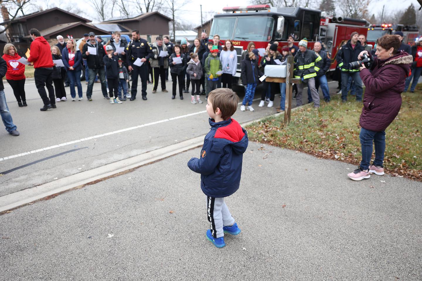 Gage Jenicek, 5, watches as volunteers sing holiday songs at one of their four stop delivering gifts to families in the community on Saturday, Dec. 10, 2022, in Lockport.