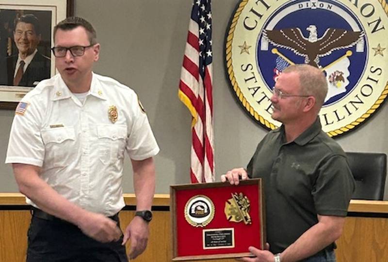 Dixon Fire Chief Ryan Buskohl (left) presents retired firefighter David Boucher with a collection of fire memorabilia April 15, 2024, at Dixon City Hall.