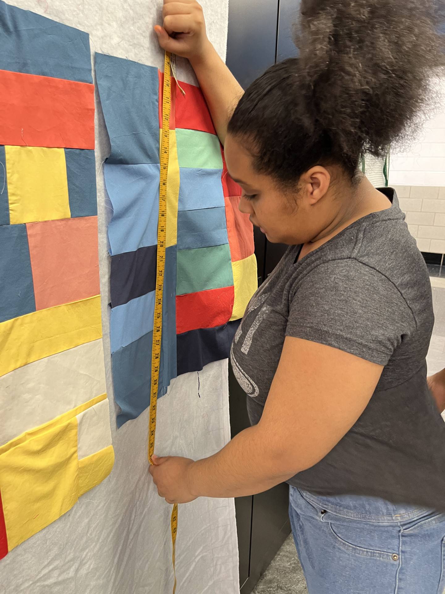Angel Colyar, a client who receives services at UCP-Center for Disability Services in Joliet, measures a section of the quilt to see how many more pieces she needs to add to make it the right size. The quilt will be actioned at the 28th Great Chefs Tasting and Auction on March 2 at the Bolingbrook Golf Club.