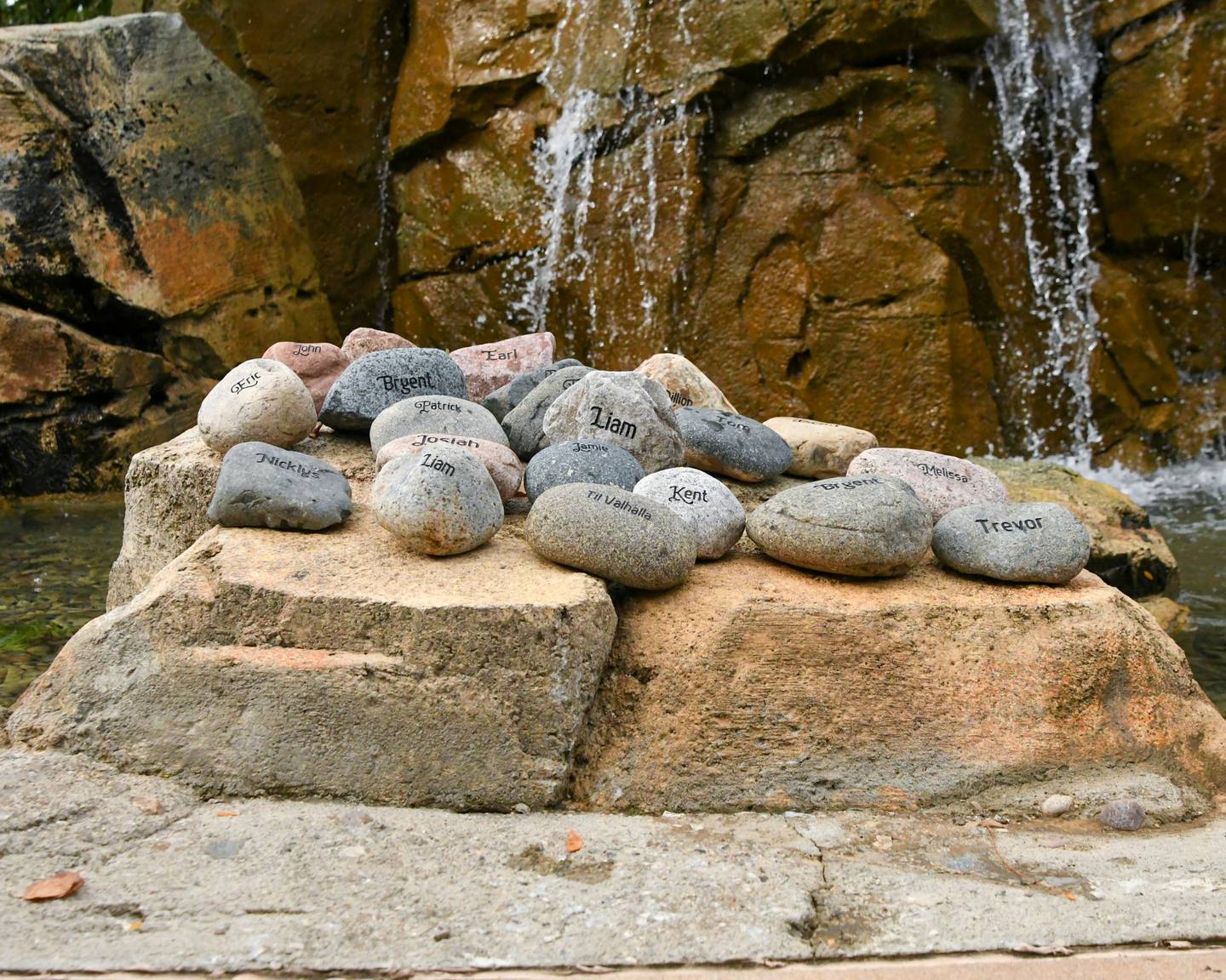 The name of a military soldier and veterans are carved on 22 rocks of those who have taken their own life sit next to a waterfall at the Kishwaukee Health & Wellness Center in Sycamore on Sunday Sept. 21, 2025, before the start of the Be the One Walk. The rocks were then carried by loved ones throughout the 2.2-mile walk.