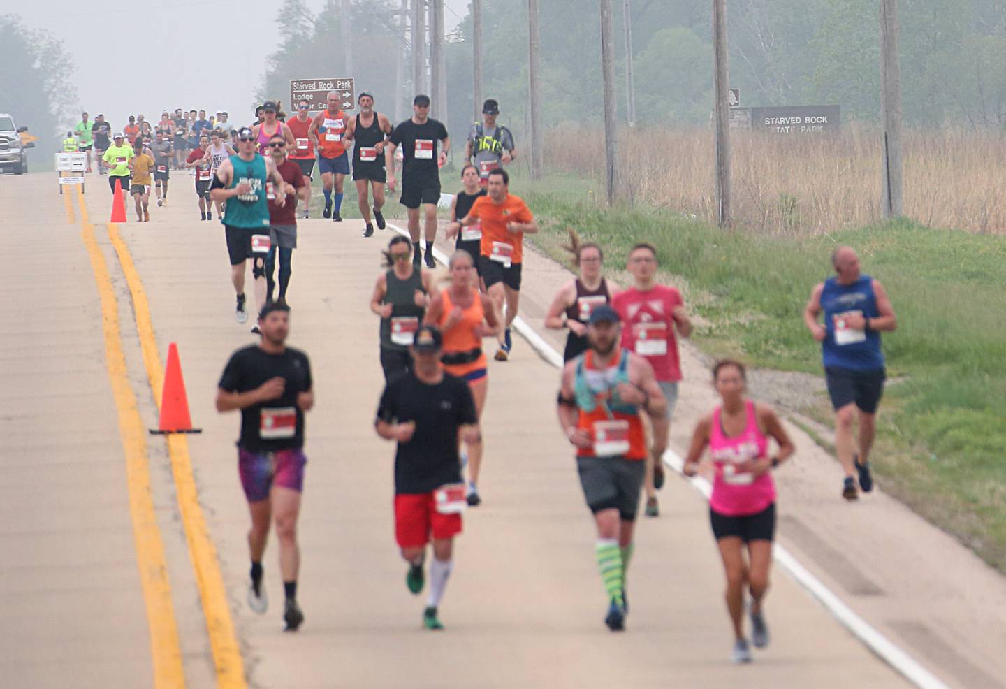 Runners pass the Illinois Route 71 entrance to Starved Rock State Park during the Starved Rock Country Marathon and Half Marathon on Saturday, May 13, 2023 at Starved Rock State Park.
