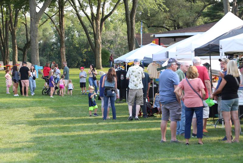 People mingle between booths during the Friday Night Market's event on Friday, Aug. 18, 2023 at Kirby Park in Spring Valley. These well-loved markets, traditionally held on the third Friday of each month, moved from the downtown location in the mini park to the captivating and spacious Kirby Park. Fireworks concluded the event.