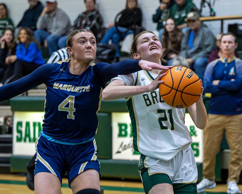 Hunter Hopkins (4) of Marquette reaches over shoulder of Parker McClain (21) of St. Bede as she drives for layup on Friday, January 16, 2026 at St. Bede Academy in Peru.