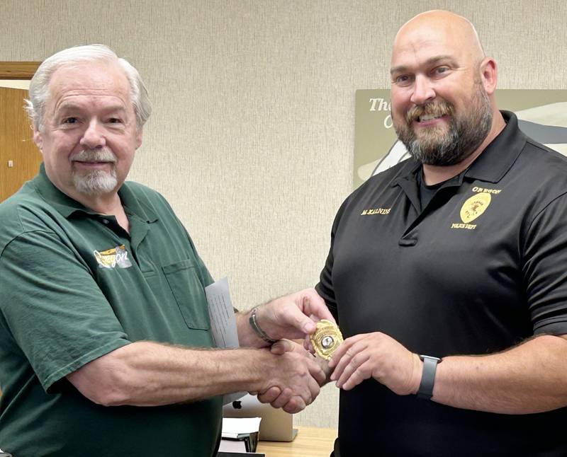 Oregon Mayor Ken Williams (left) hands  Matt Kalnins his new badge after the city council hired Kalnins as Oregon's new police chief on Tuesday, Aug. 13, 2024.. Kalnins had been serving as interim chief.