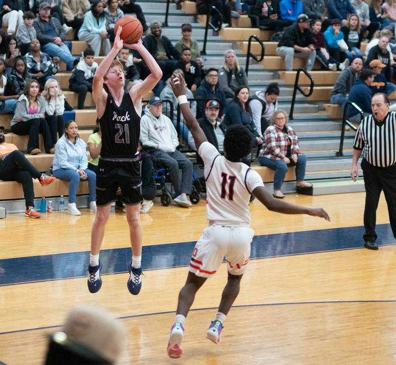 Oswego East's Andrew Pohlman (21) shoots a three pointer against Oswego’s Rodney Richardson (11) during a basketball game at Oswego High School on Tuesday, Dec 12, 2023.