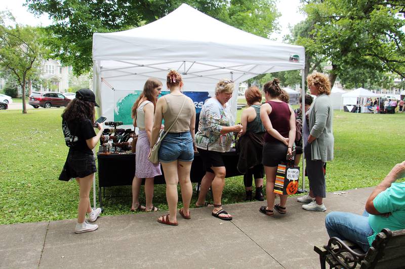 Shoppers look at items at the Uniquely Yours tent Saturday, July 1, 2023 during Petunia Fest's Nuts About Art show at John Dixon Park in Dixon.