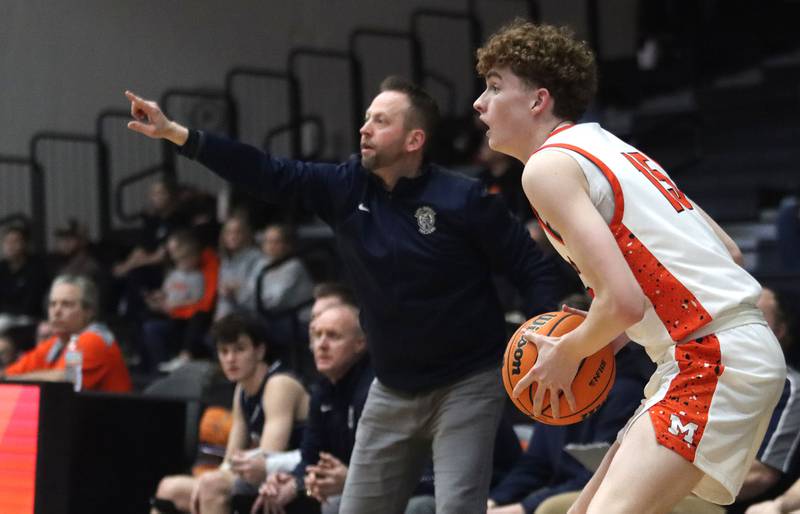 McHenry’s Parker Ostertag, right, looks for an option as Cary-Grove’s Head Coach Adam McCloud guides the Trojans in varsity boys basketball on Tuesday, Feb. 17, 2026, at McHenry High School in McHenry.