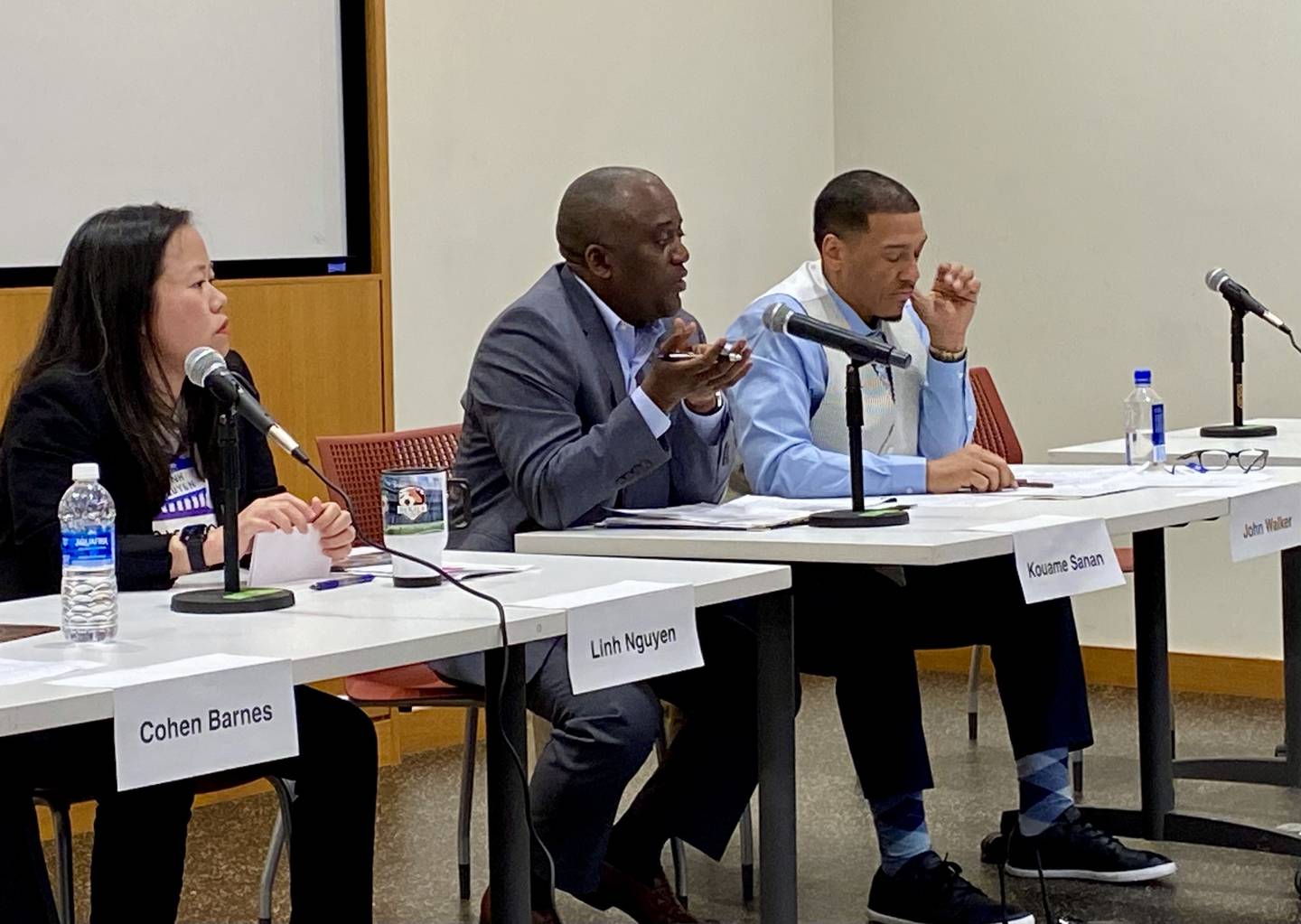 DeKalb mayoral hopeful Kouame Sanan (middle) answers a question as opponents Linh Nguyen (left) and John Walker (right) listen at a candidate forum hosted by WNIJ radio and the DeKalb Election Group on Sunday, March 9, 2025, at the DeKalb Public Library, 309 Oak St.