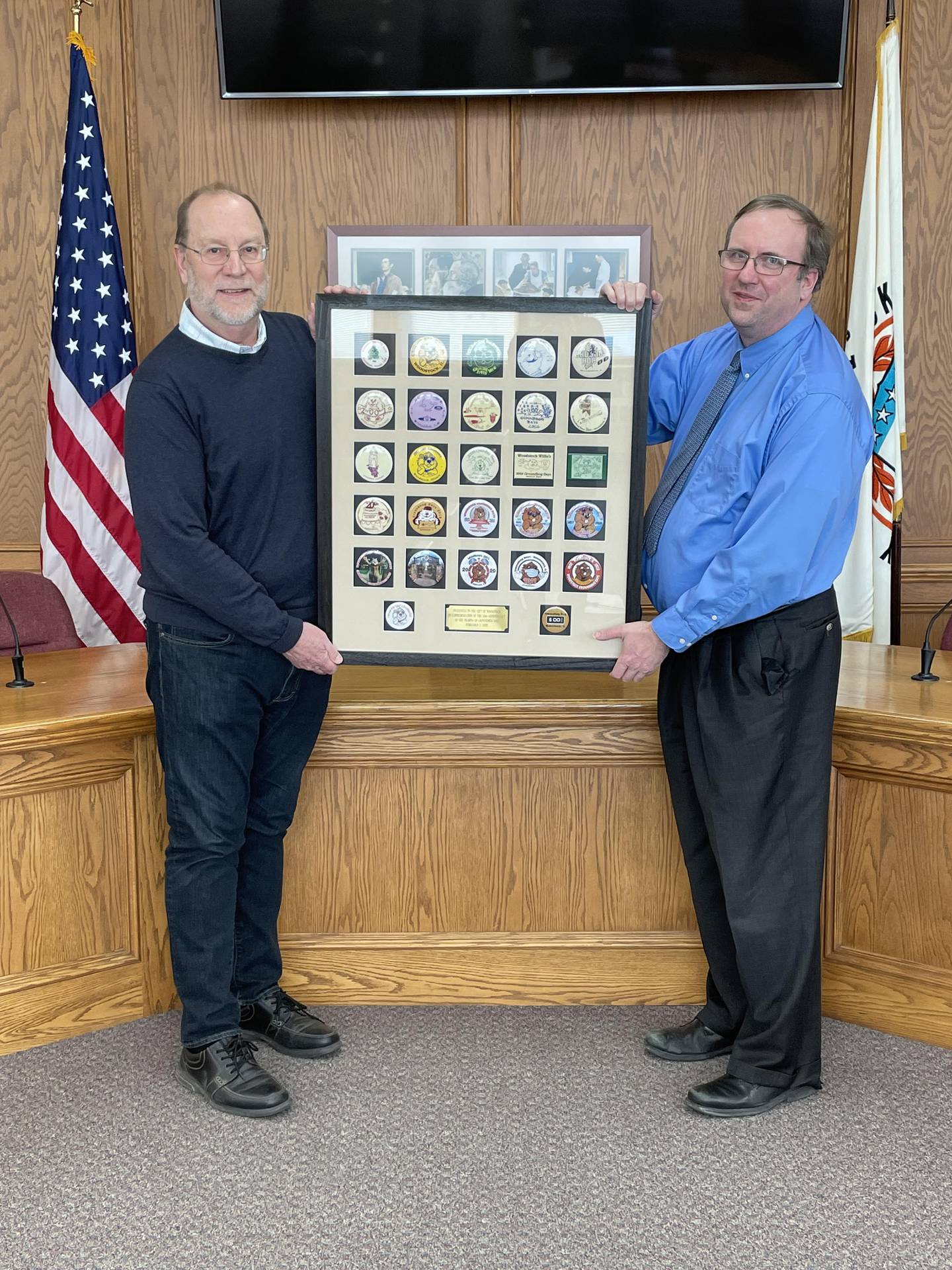 Woodstock City Manager Roscoe Stelford, right, and Rick Bellairs of the Groundhog Days Committee show a framed display of all the commemorative buttons created to mark each year of the city's February Groundhog Days celebration in commemoration of downtown Woodstock serving as the film set for the 1993 classic comedy "Groundhog Day," starring Bill Murray.
