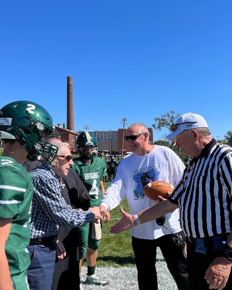 WWII veteran Melvin Baima ’38 delivers the game ball on Saturday and shakes hands with Bruin football coach Jim Eustice. Biama, who is 100 years old, was on campus celebrating his 83rd class reunion. He is the great-grandfather of John and Ryan Brady, senior football captains who are also pictured here with Baima.