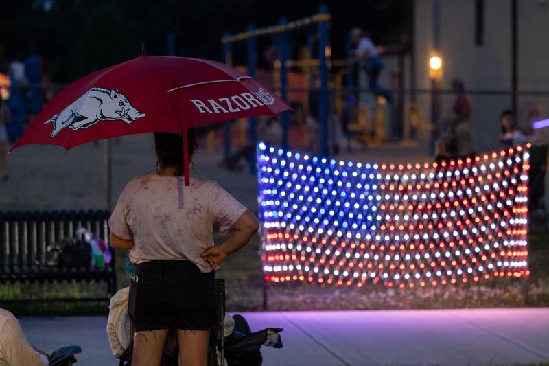 Monica Garcia holds umbrella in anticipation of rain near American flag on Saturday, July 5, 2025 on Canal Street in Utica.