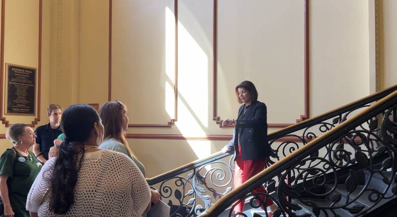 Northern Illinois University President Lisa Freeman checks her watch as she walks down a staircase to meet with members of AFSCME Local 1890 on Sept. 16, 2025. Those union workers wanted to hand-deliver a message regarding ongoing contract negotiations between the union and the university.