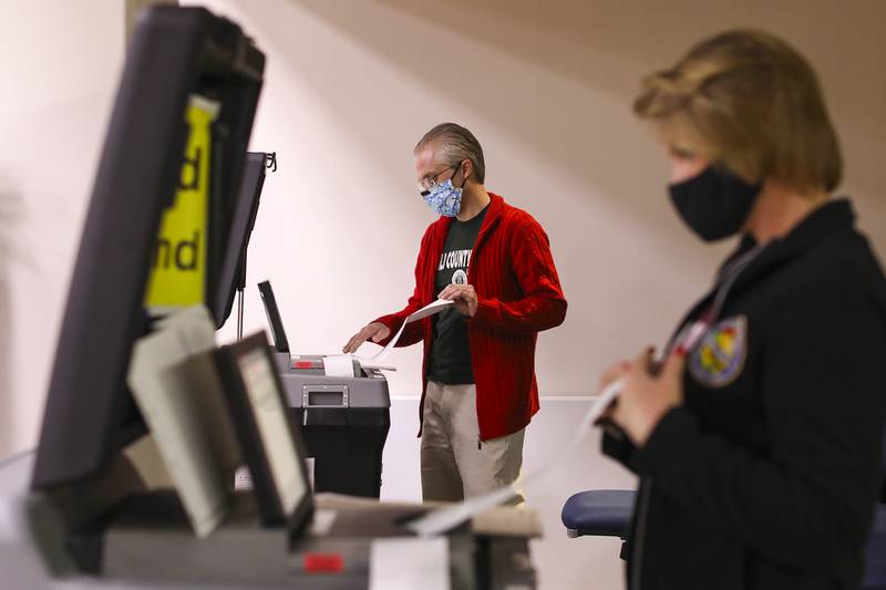 Election officials feed ballots into a counting machine on Wednesday, April 14, 2021, at Will County Office Building in Joliet, Ill.