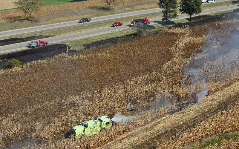Peru firefighters use the Illinois Valey Regional Airport fire truck to extinguish a brushfire (bottom) as Malden firefighters (top) douse flames on Wednesday, Oct. 9, 2024 along Interstate 80 in the eastbound lane near mile post 65 in Bureau County.  A MABAS box alarm was sent out around 11:45 a.m. and upgraded to a fourth-alarm. Interstate 80 was shut down in the Eastbound lane while firefighters doused the flames. Fire companies from Utica, Oglesby, Ladd, Bureau, Hennepin, Peru, La Salle, Spring Valley and others responded to the scene.