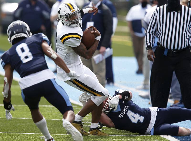 Nazareth’s Peter Roll (right) tries to tackle St. Laurence’s Darius Wilson during their football game at Nazareth Academy in LaGrange Park, Ill., on Saturday, March 27, 2021.