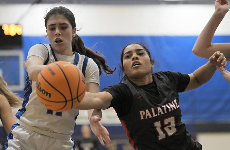 Palatine’s Alexia Washington stretches for the ball against Wheaton North’s Maya Merrifield in a girls basketball game in Wheat on Monday, Dec. 22, 2025.