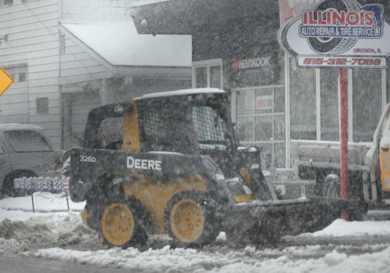 An Oregon business owner uses a skid loader to move the wet, heavy snow that fell across the region on Tuesday, Jan. 9, 2024.
