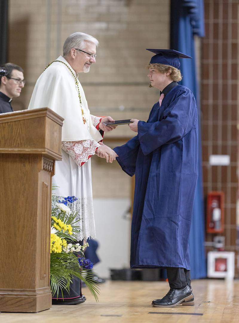 Monsignor Philip Halfacre hands Jack Williamson his diploma during a commencement ceremony on Sunday, May 25, 2025 in Bader Gymnasium at Marquette High School.