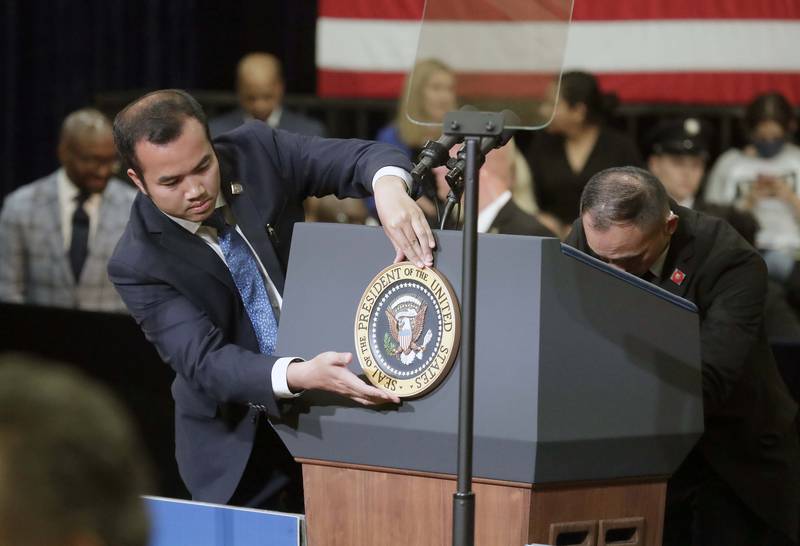 An unidentified person from the White House communication agency places the presidential seal before President Joe Biden speaks at McHenry County College Wednesday, July 7, 2021, in Crystal Lake.