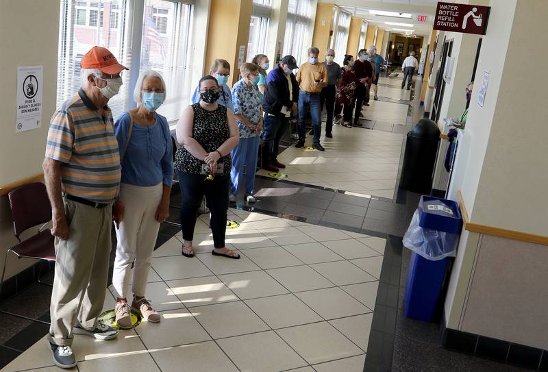 Don and Joyce Novack of Algonquin, front, wait in a line stretching down the hallway of the McHenry County Administration Building for early voting on Thursday, Sept. 24, 2020 in Woodstock.  The site, located at 667 Ware Road in Woodstock, will be the only place to vote before early voting begins throughout the county on Oct. 19.