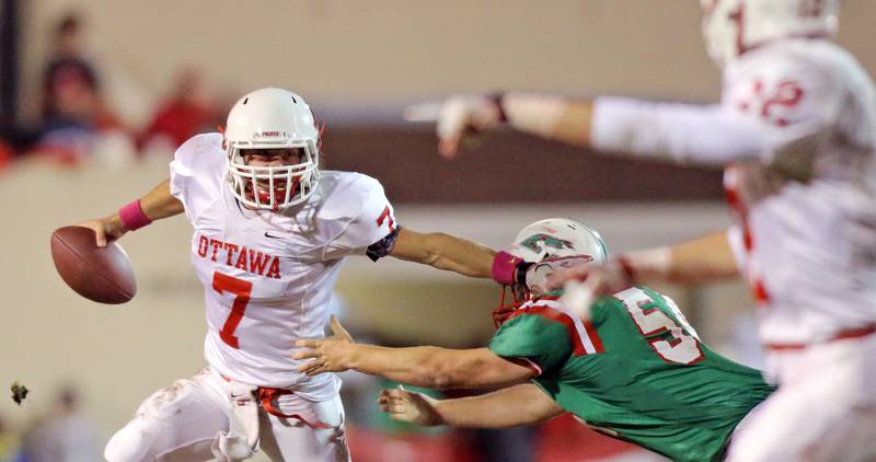 Ottawa quarterback Will Hoffman (7) looks to get the ball to J.D. Bryant (12) while trying to avoid being tackled during the 2012 game against La Salle-Peru at Howard Fellows Stadium.