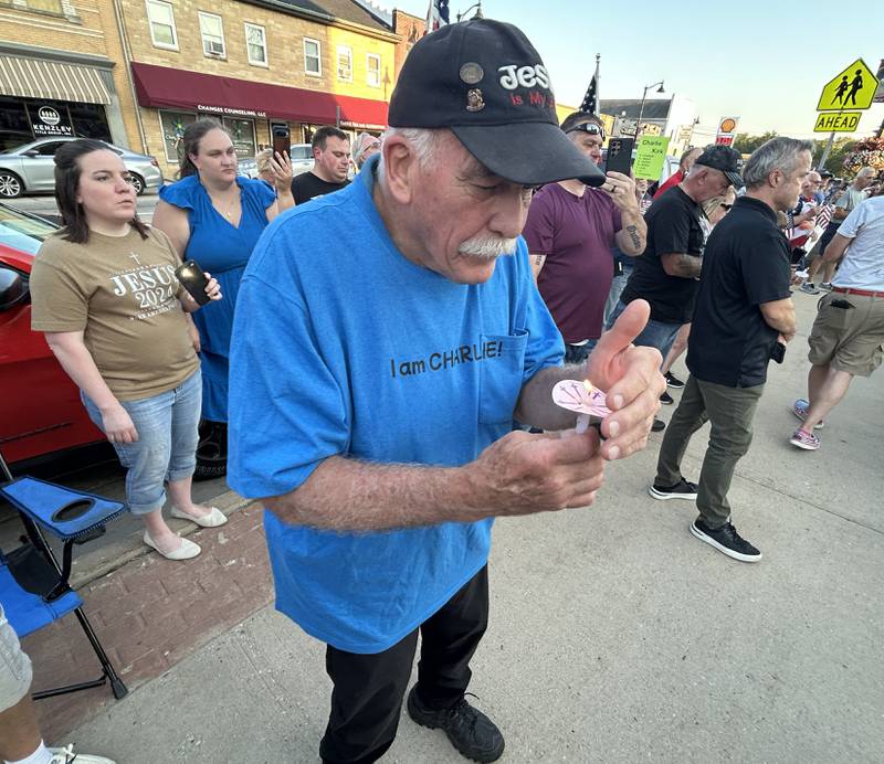 John Tuttle of Oregon, shields his candle's flame from the wind during a candlelight vigil for Charlie Kirk in front of the historic Ogle County Courthouse in downtown Oregon on Sunday, Sept. 14, 2025.
