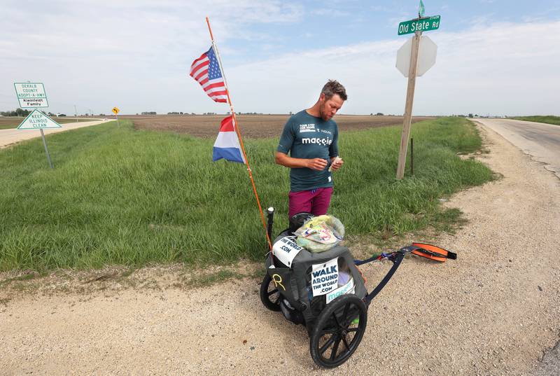 Tom Boerman, from the Netherlands, has a drink and eats lunch during a break from walking Tuesday, May 24, 2022, at the intersection of Old State and Ault Roads near Kirkland. Boerman, who stopped for the nightat a home in DeKalb, is on a quest to walk around the world while raising money for schools in Nepal that were hit hard by the 2015 earthquake in the region.