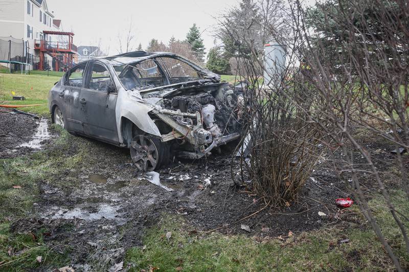 The remains of a vehicle that crashed into a neighborhood backyard near Huntley on Thursday afternoon, April 14, 2022. The vehicle had crashed into a pole, flipped over and ended in the yard before catching fire, police officials said.