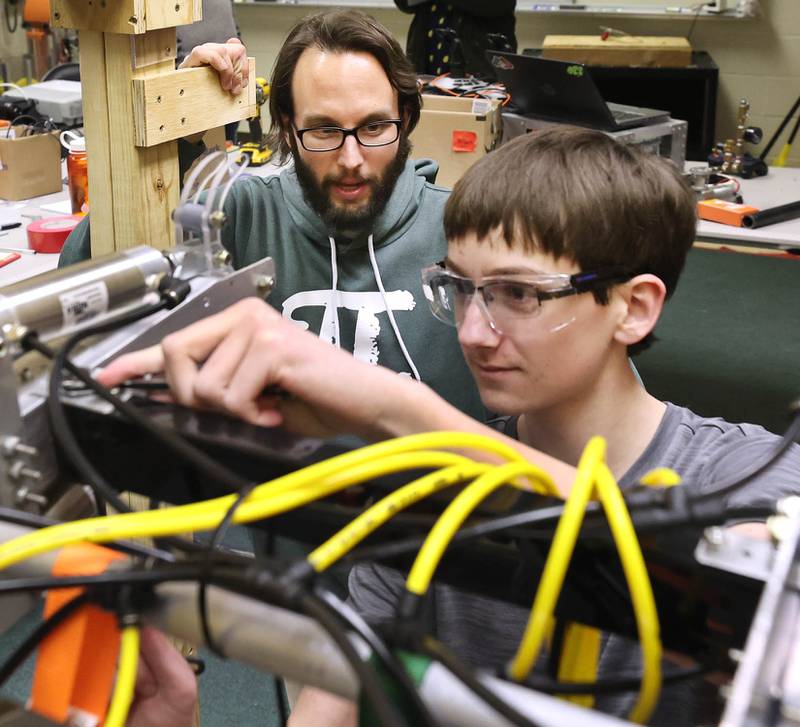 Michael Lofthouse, "Crowbotics" team faculty advisor and math teacher at DeKalb High School, works with freshman Blake Bollow on the team's robot Thursday, March 10, 2022, at Huntley Middle School in DeKalb. The team is preparing for a competition that begins in early April.