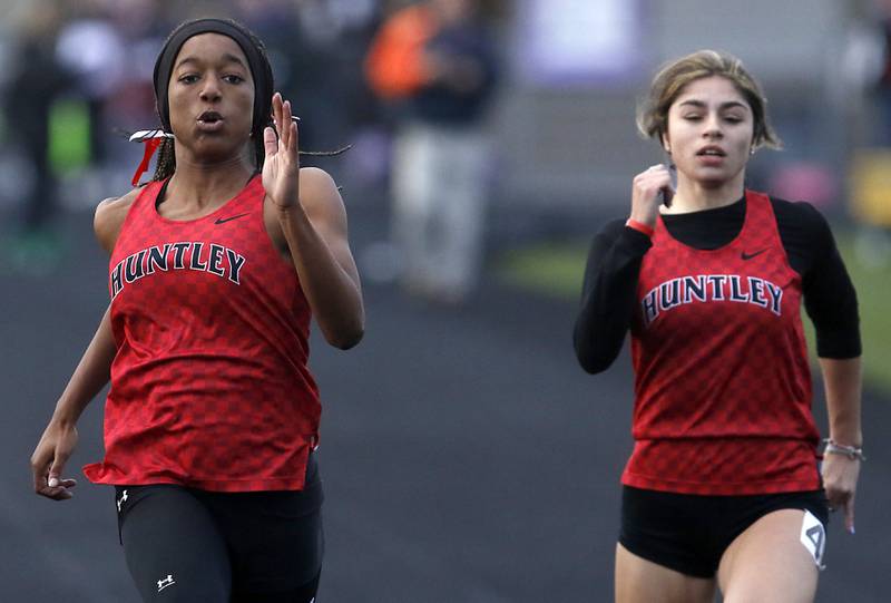 Huntley’s Alex Johnson and Vicky Evtimov race to the finish line in the 100 meter dash during Fox Valley Conference girls track and field meet Friday, May 6, 2022, at Hampshire High School.
