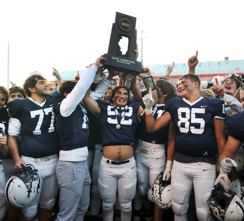 Cary-Grove players hoist the trophy Saturday, Nov. 25, 2023, after their win over East St. Louis in the IHSA Class 6A state championship game in Hancock Stadium at Illinois State University in Normal.