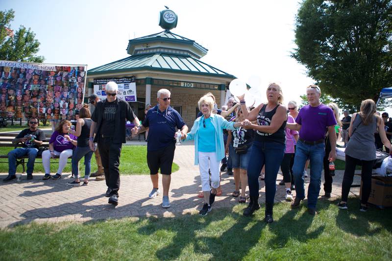 Families who have lost loved ones to  fentanyl poisoning walk together to release a ballon cross necklace that has messages to their lost loved ones at the  9th Annual Ride for John and JohnFest for my child's life matters on Saturday Aug.2, 2025 in Carol Stream.
