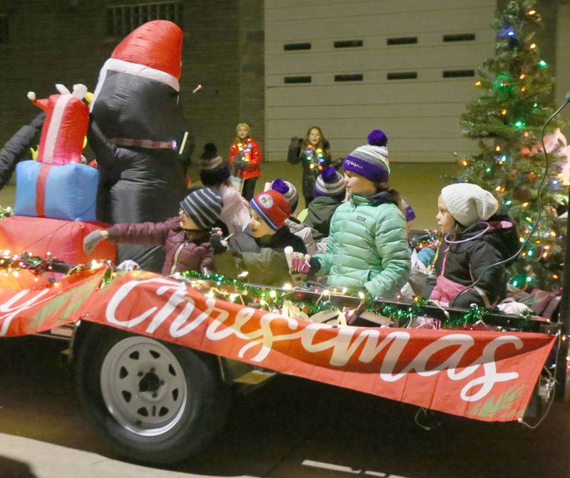 Kids wave while riding a Christmas float during the Light up the Night parade on Saturday, Dec. 3, 2022 downtown Peru.