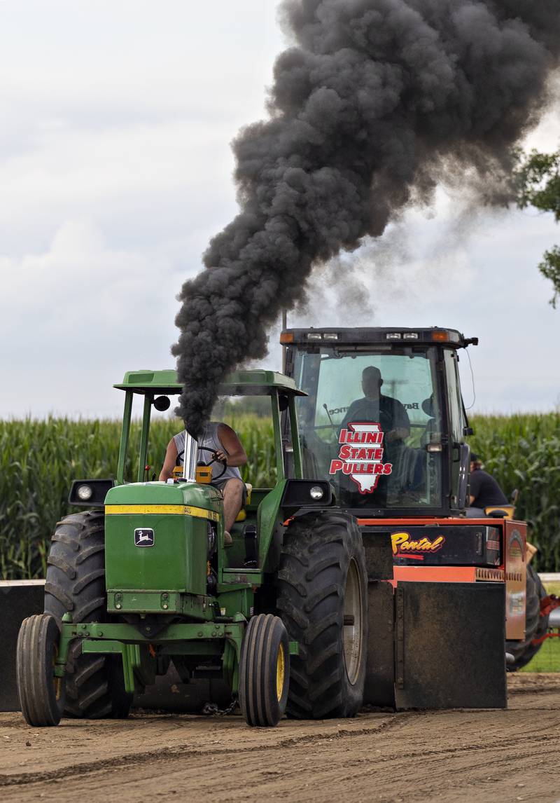 Jim Young’s John Deere belches out black smoke as he revs the rpm’s Thursday, July 24, 2025, for his run in the tractor pulls. The fair had two classes of tractors competing for the night, the Backroad Pullers and the Farmstock Pullers.