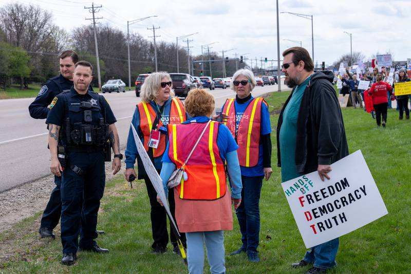 Police discuss with Hands Off organizers about a verbal altercation with a anti-Trump person and a Trump supporter in a car that stopped in front of the line of protesters along Randall Road in South Elgin, IL on Saturday April 19, 2025.  Hundreds of protesters participated in the latest Hands Off protest occurring in the Chicagoland area and the rest of the country.