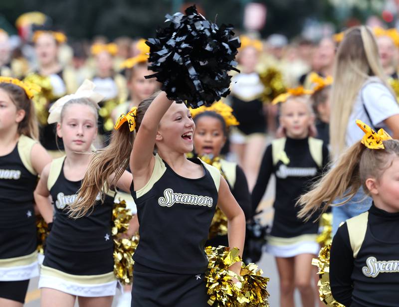 Members of the Sycamore Youth Football cheer team wave to spectators as they make their way down State Street Wednesday, Sept. 20, 2023, during the Sycamore High School homecoming parade.