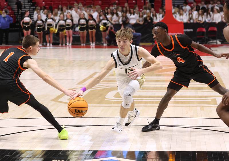Sycamore's Xander Lewis drives between DeKalb's Jackson Kees (left) and Marquise Bolden during their game Friday, Jan. 31, 2025, in the FNBO Challenge in the Convocation Center at Northern Illinois University in DeKalb.
