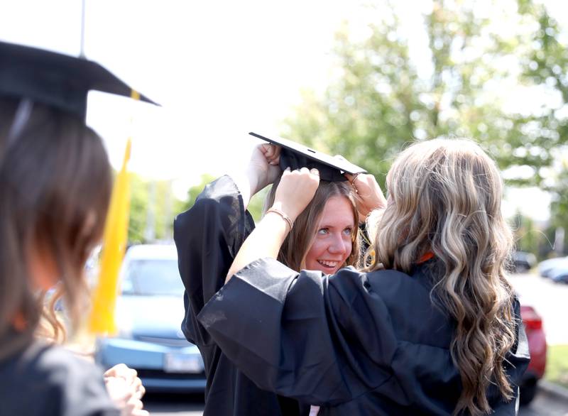 Samantha Wills (right) helps Kaley McCabe with her cap before the Wheaton Warrenville South commencement ceremony on Saturday, May 24, 2025 at the College of DuPage in Glen Ellyn.