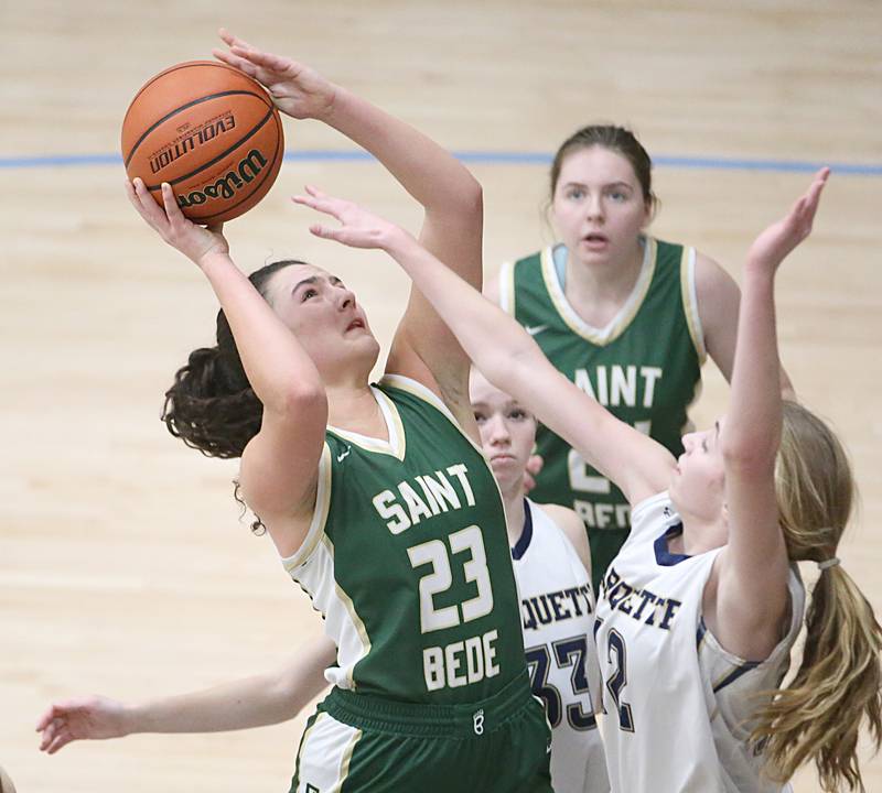 St. Bede's Ali Bosnich squeezes into the lane to score over Marqutte's Lily Craig in Bader Gymnasium on Wednesday, Feb. 8, 2022 at Marquette High School.