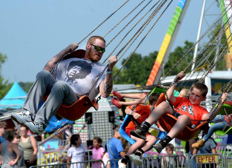 John Foresythe, of Lanark, (left) and his nephew, Ian, ride the swings at the carnival at the Ogle County Fair on Friday, Aug. 2, 2024 west of Oregon.