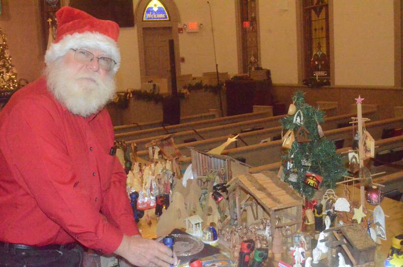 Santa adjusts lighting on one of 60 nativity sets displayed Friday evening, Dec. 5, 2025 at Church of the Good Shepherd United Methodist of Oswego. The 21st annual display and a chili and pie supper was held by Good Shepherd United Women in Faith during Oswego's annual Christmas Walk.