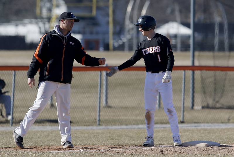 Crystal Lake Central coach Andy Deain first bumps Crystal Lake Central's Drew Welder after he made it to third base during a nonconference baseball game against Boylan Wednesday, March 29, 2023, at Crystal Lake Central High School.