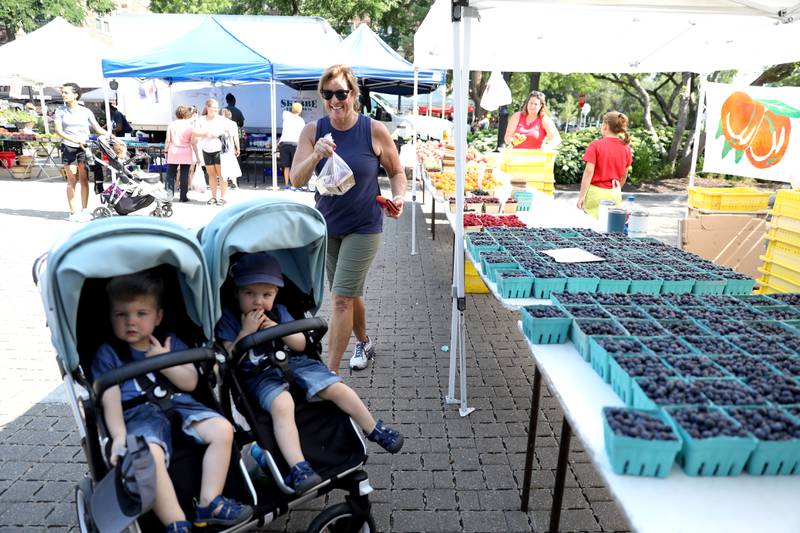 Karen Funk purchases berries with her 22-month-old twin grandsons Arthur (left) and Ambrose Funk at the weekly farmer’s market in La Grange on Thursday, July 20, 2023.
