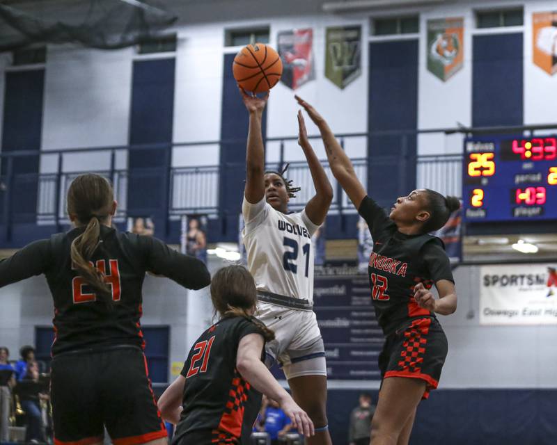 Oswego East's Desiree Merritt (21) hangs in the air for a jump shot over Minooka's Kendall Thomas (3) during their basketball game between Minooka at Oswego East Friday, Jan 16, 2026 in Oswego.